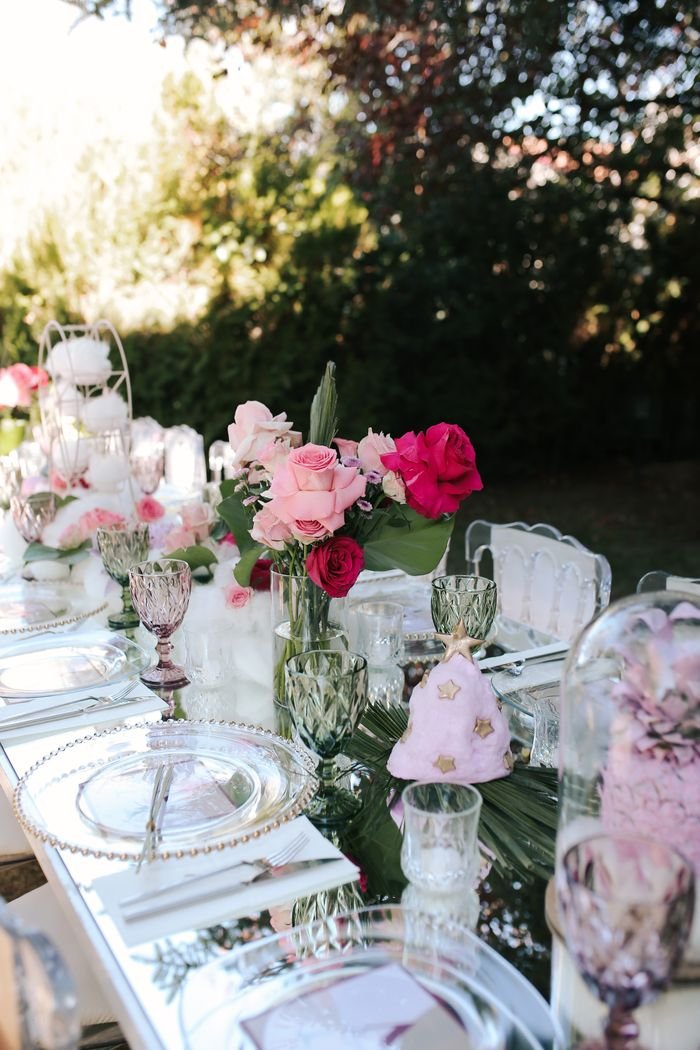About A beautifully decorated outdoor wedding table with elegant pink flowers and glassware.