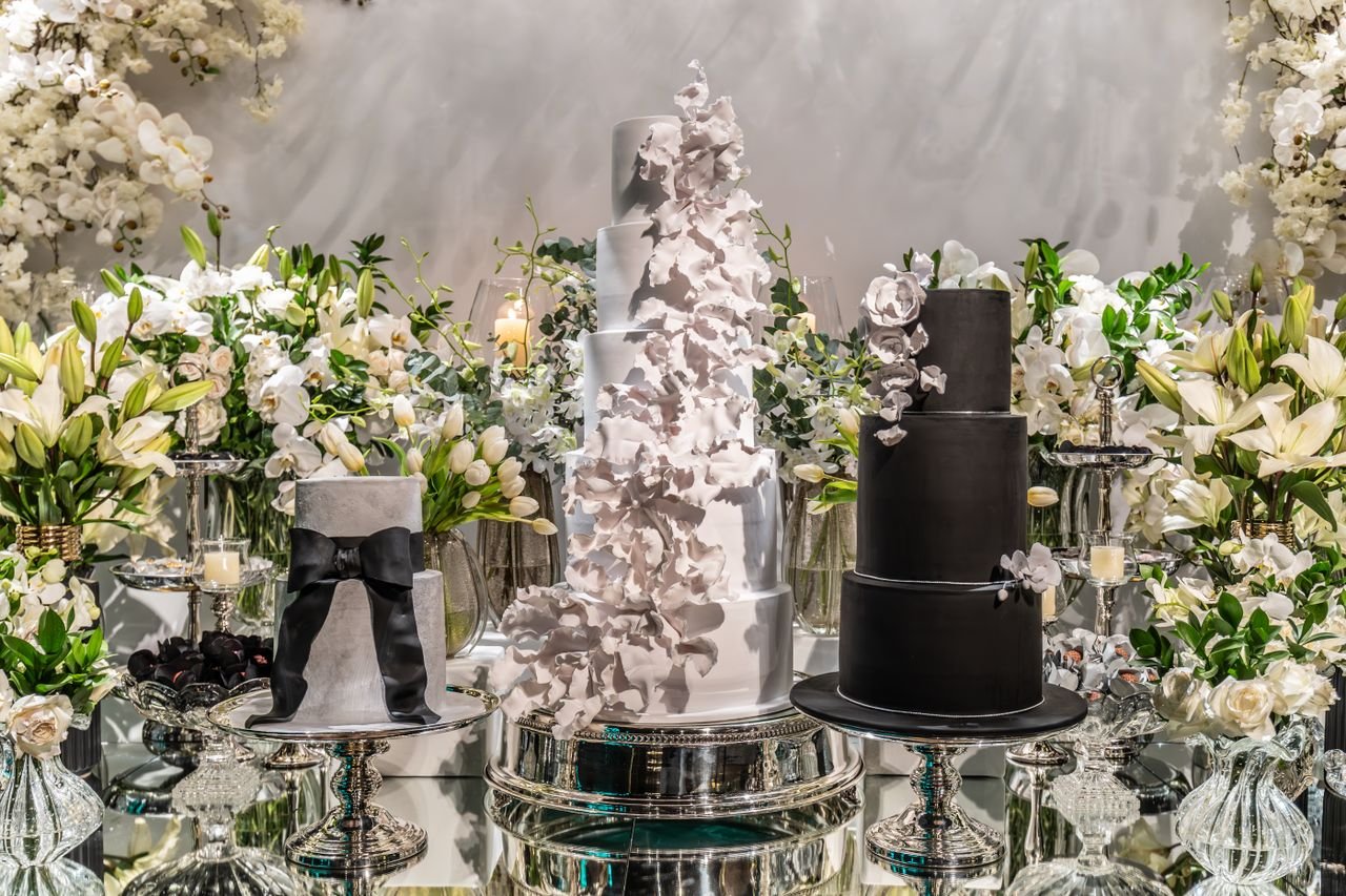 Luxurious wedding cake display surrounded by elegant flower arrangements.